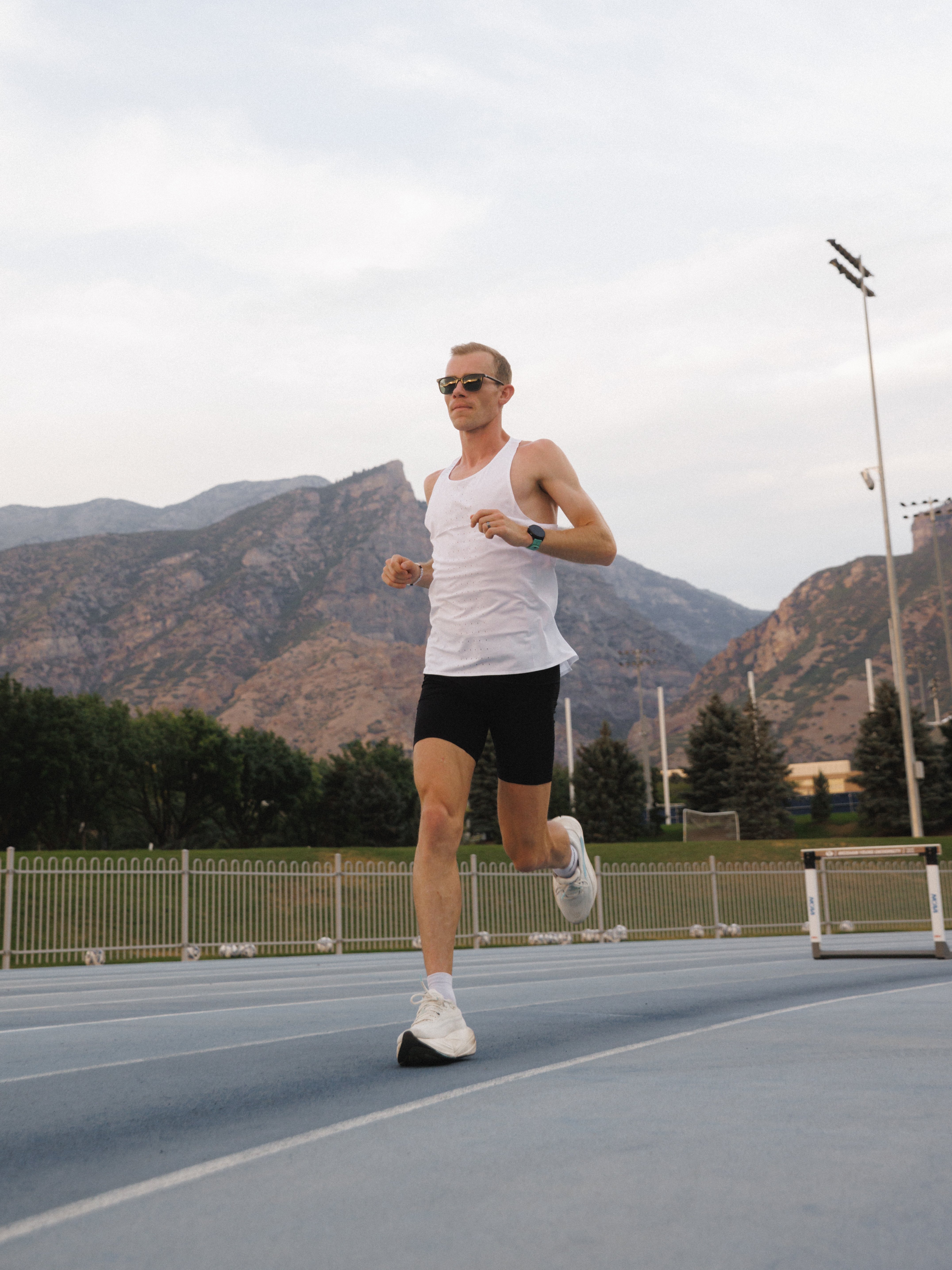 Runner wearing a sports watch on a paved road with mountains in the background